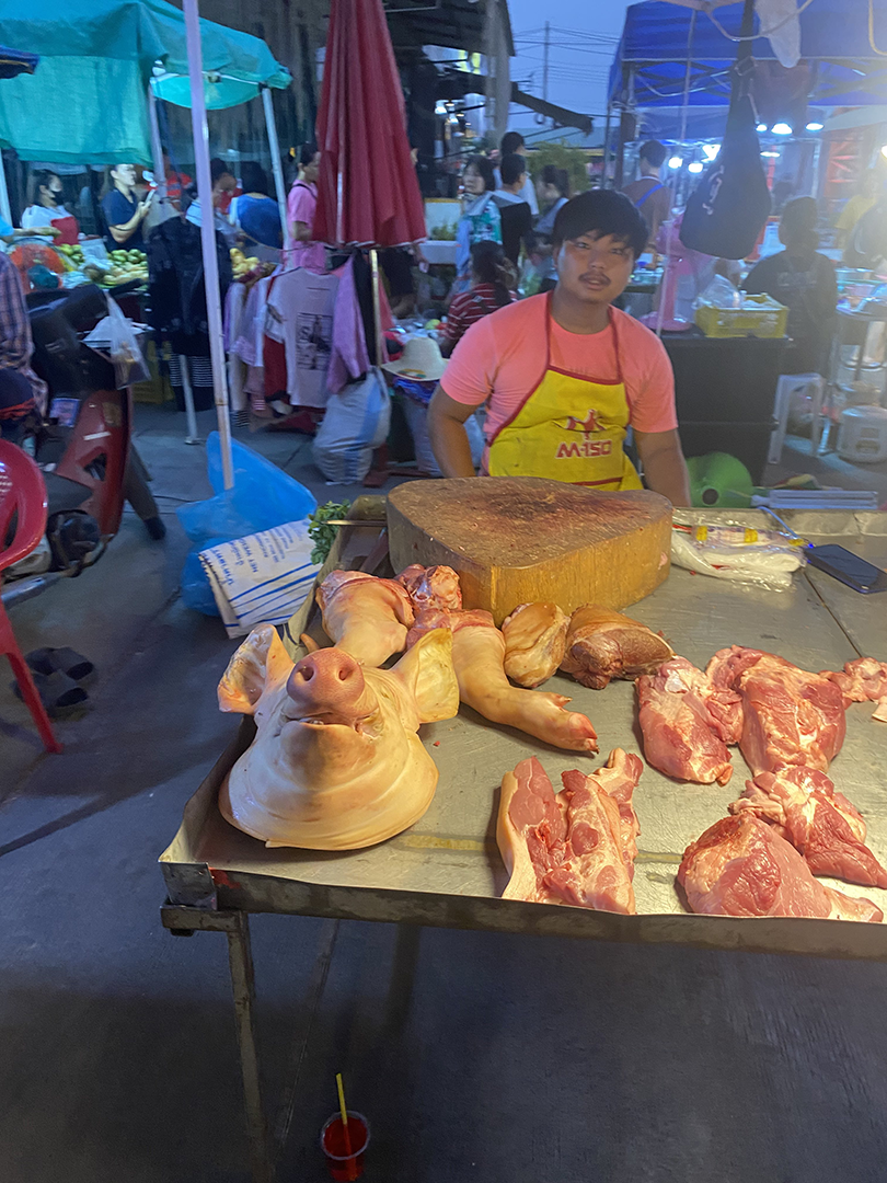Seller with various pork parts, including a pig head