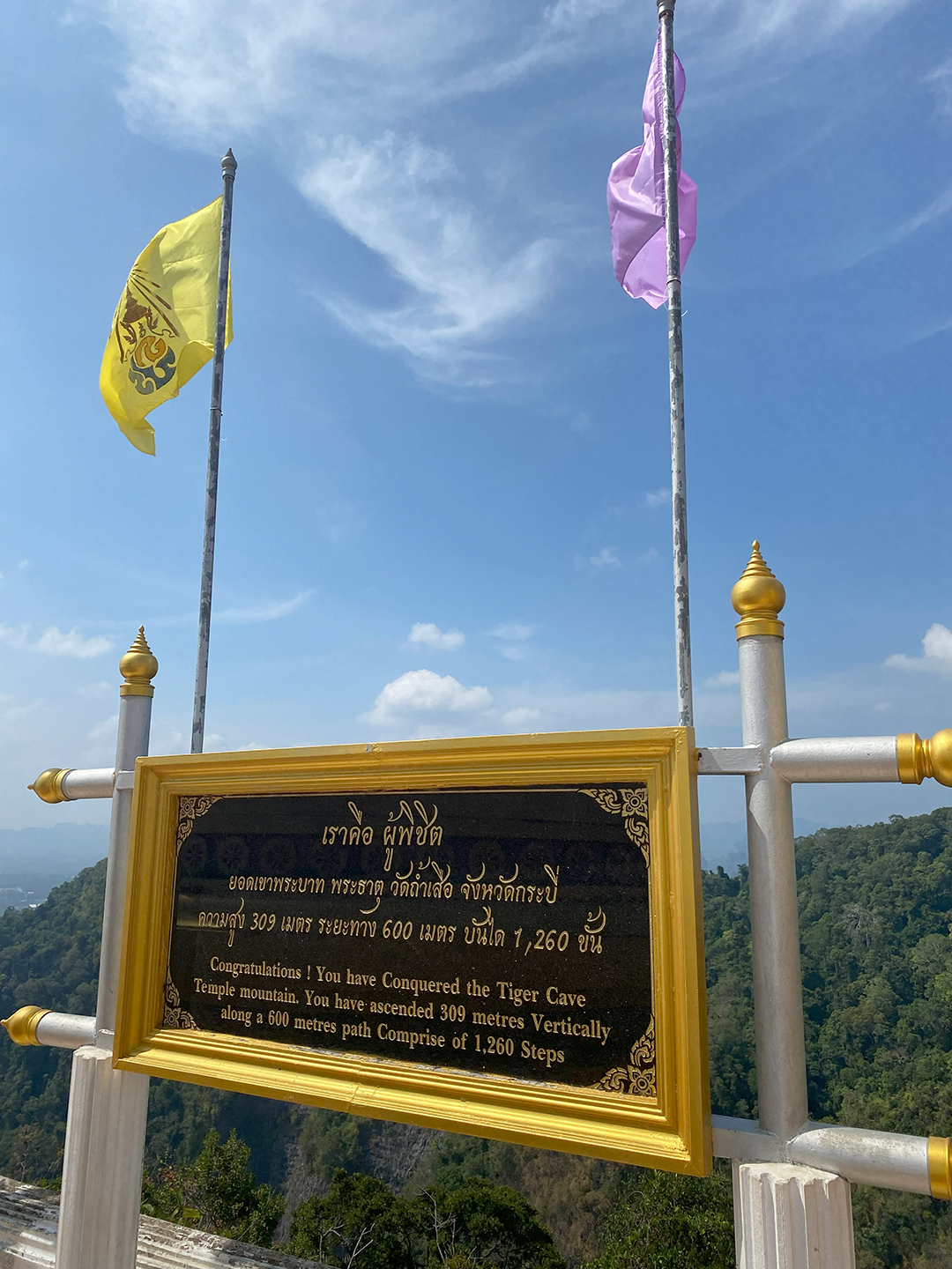 Gold-plated sign congratulating hikers who successfully climbed the Tiger Cave Temple mountain. Inscription reads: 'Congratulations! You have Conquered the Tiger Cave Temple mountain. You have ascended 309 meters Vertically along a 600 metres path Comprise of 1,260 steps'