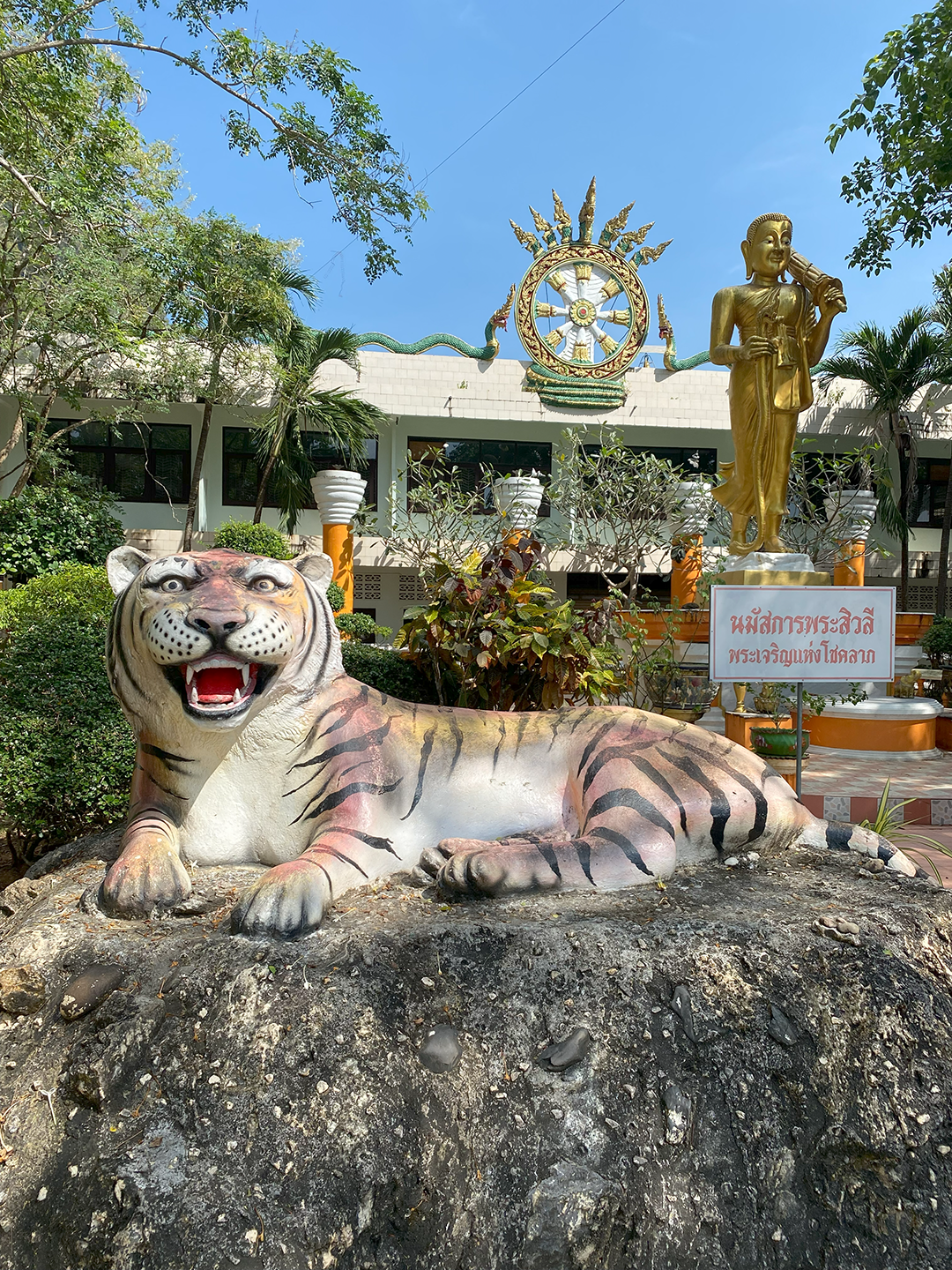 Tiger statue with building and other statues behind