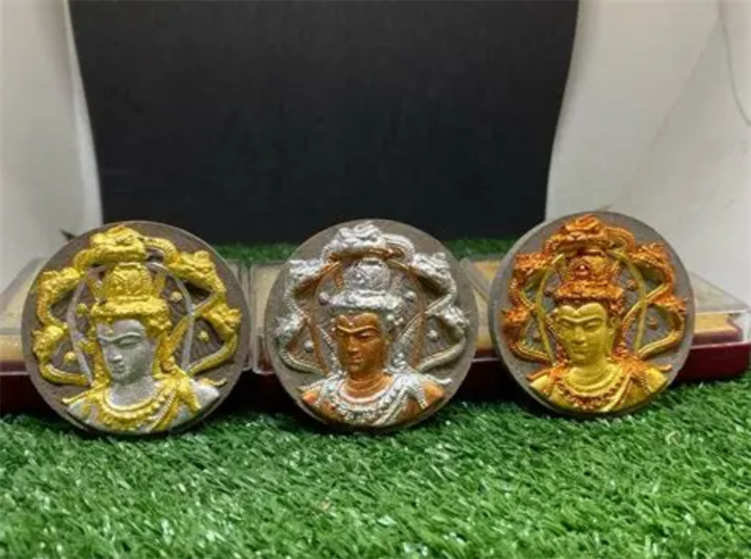 3 smilar amulets on a table, each with different color schemes.
